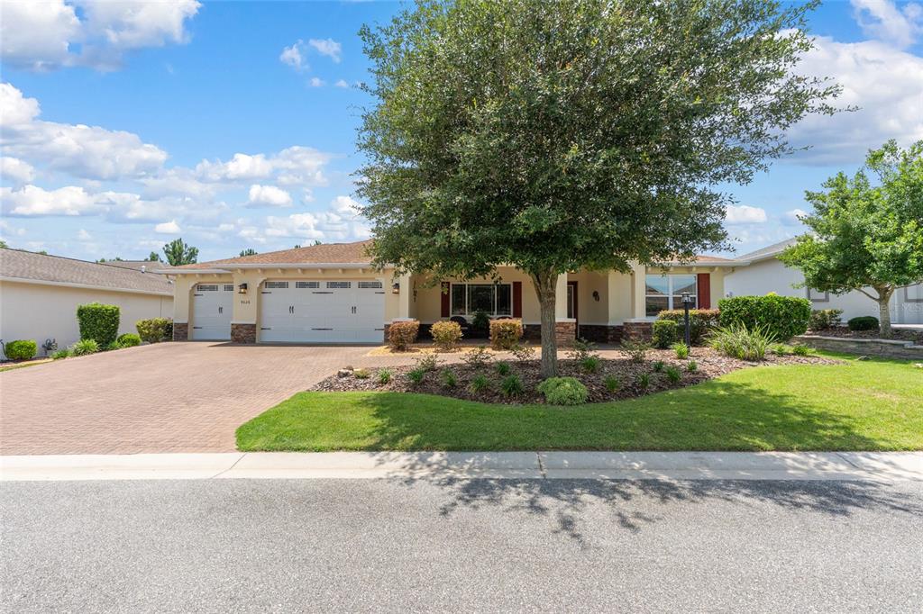 A single-story house with a paved driveway, three-car garage, and a large tree in front — 9026 SW 89TH STREET ROAD, OCALA, FL