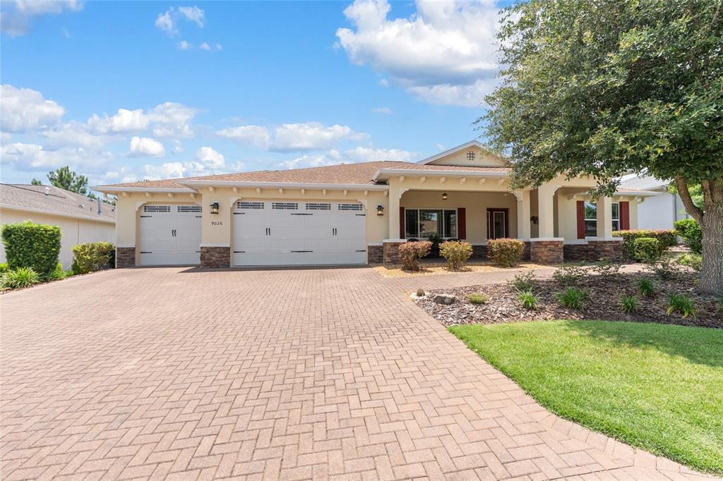 A single-story house features a brick paver driveway, a three-car garage, and stone accents — 9026 SW 89TH STREET ROAD, OCALA, FL