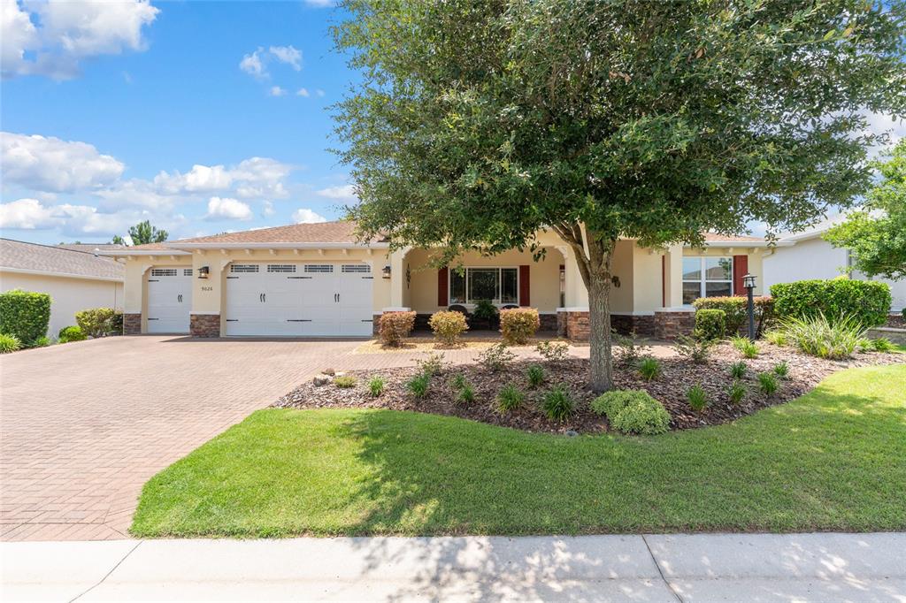 A single-story house with a brick driveway, three-car garage, and a large front yard tree — 9026 SW 89TH STREET ROAD, OCALA, FL