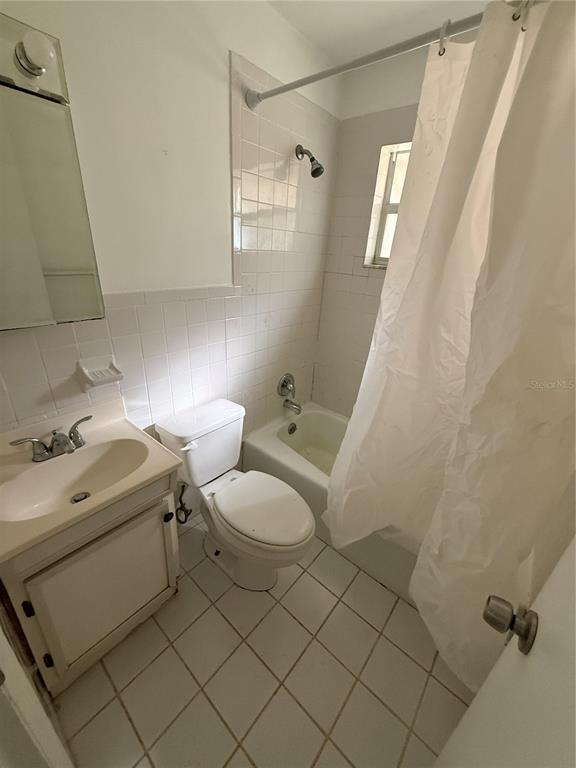 A small bathroom features a white vanity, a toilet, and a shower-tub combination with tile — 1270 8TH AVENUE NE, LARGO, FL