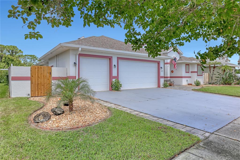 A single-story house with a two-car garage, a paved driveway, and a landscaped front yard — 4373 FLETCHER LANE, TITUSVILLE, FL