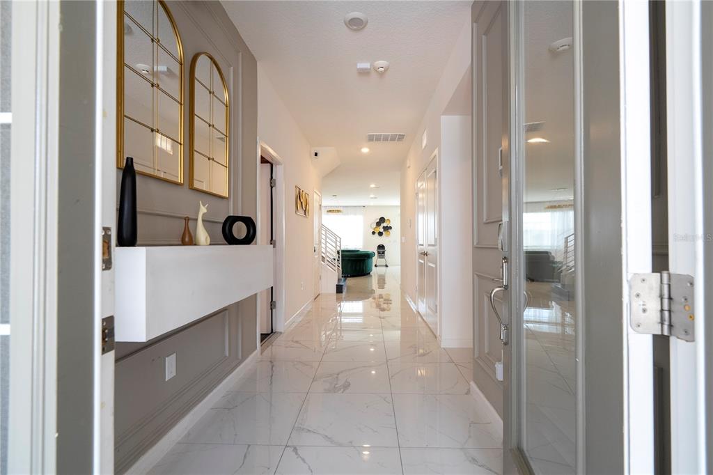 A bright entryway features white marble tile flooring, a floating shelf, and arched wall mirrors — 2512 SHANTI DRIVE, KISSIMMEE, FL