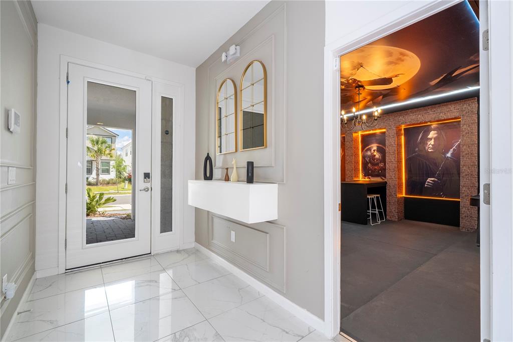 A modern entryway with white tile floors leads into a themed room featuring Harry Potter decor — 2512 SHANTI DRIVE, KISSIMMEE, FL