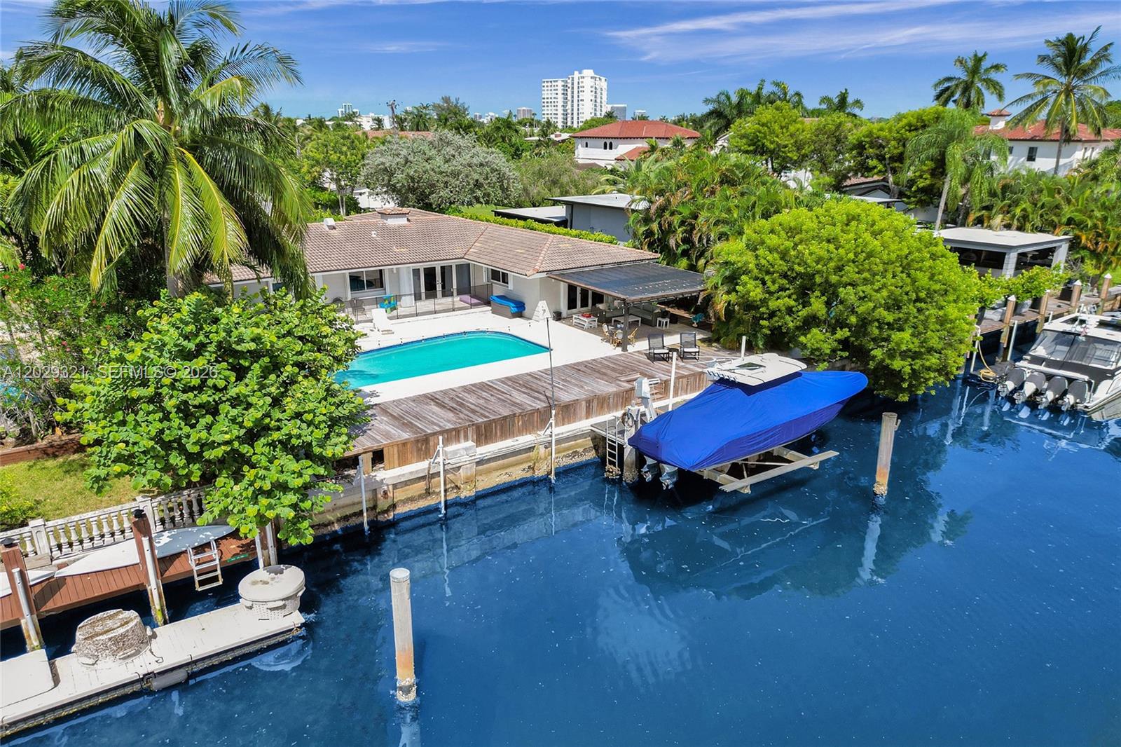An aerial view of a waterfront house with a swimming pool, wooden deck, and boat lift — 1912 NE 119th Rd # 0, North Miami FL 33181, NORTH MIAMI, FL