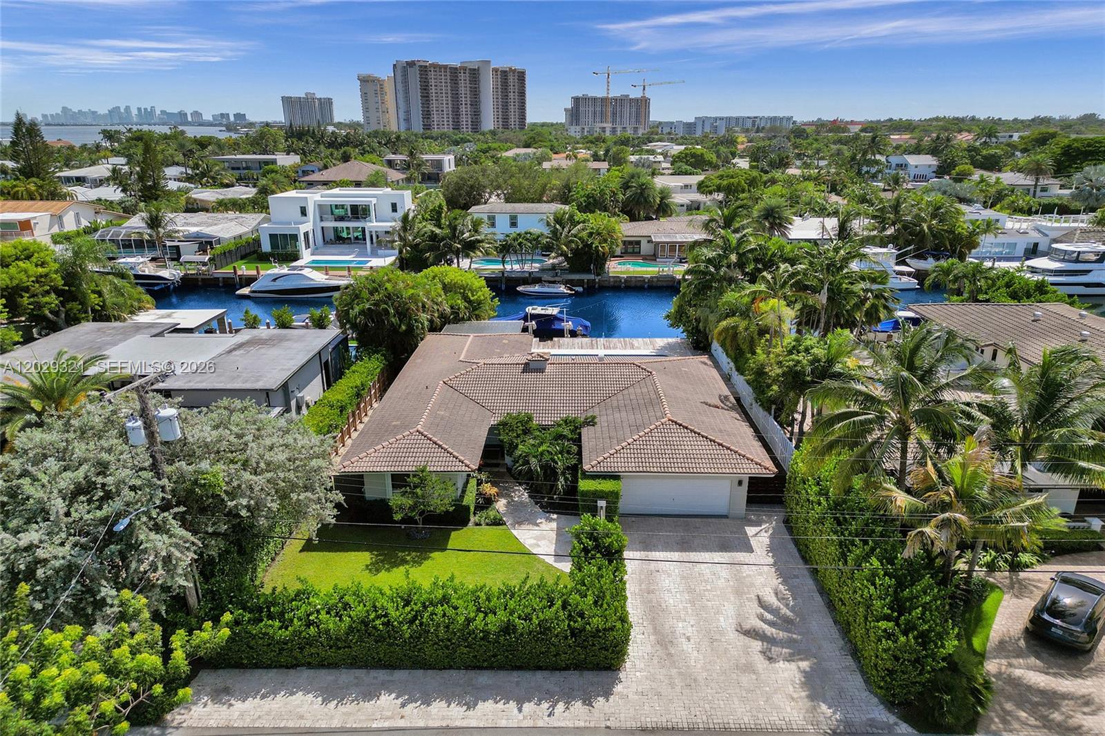 An aerial view shows a single-story house with a tiled roof, driveway, and backyard canal — 1912 NE 119th Rd # 0, North Miami FL 33181, NORTH MIAMI, FL