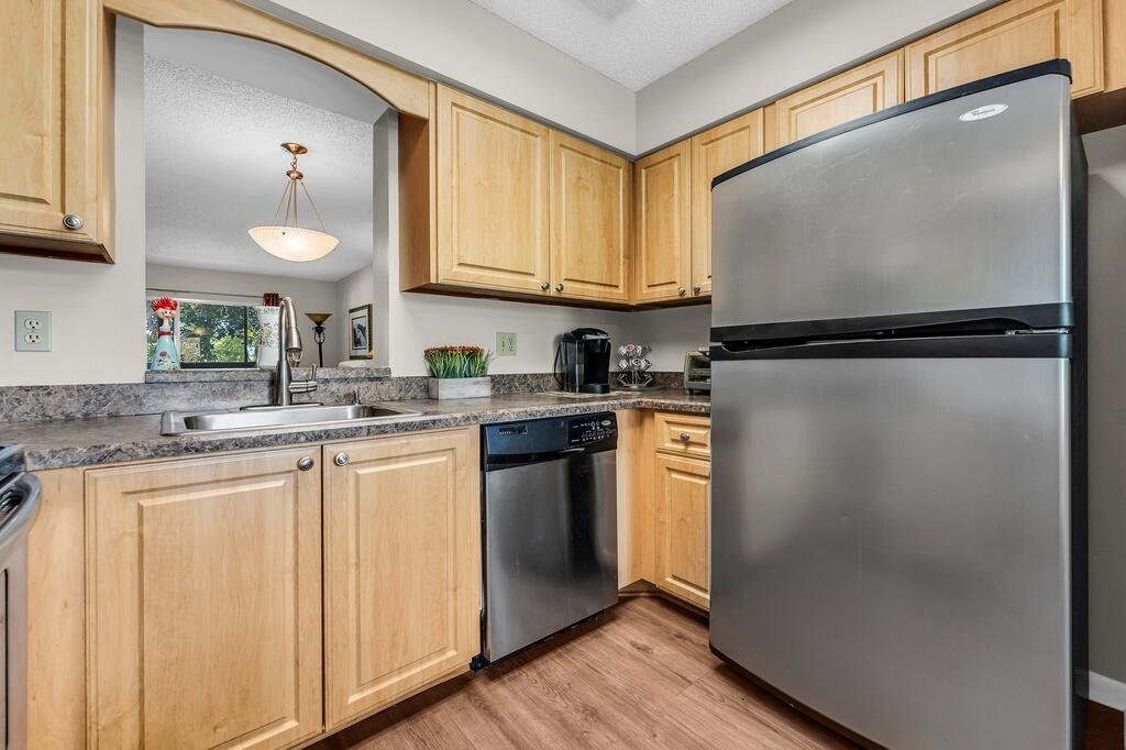 A kitchen with light wood cabinets, stainless steel appliances, and a pass-through window — 7341 Amberly Lane # 307, Delray Beach FL 33446, DELRAY BEACH, FL
