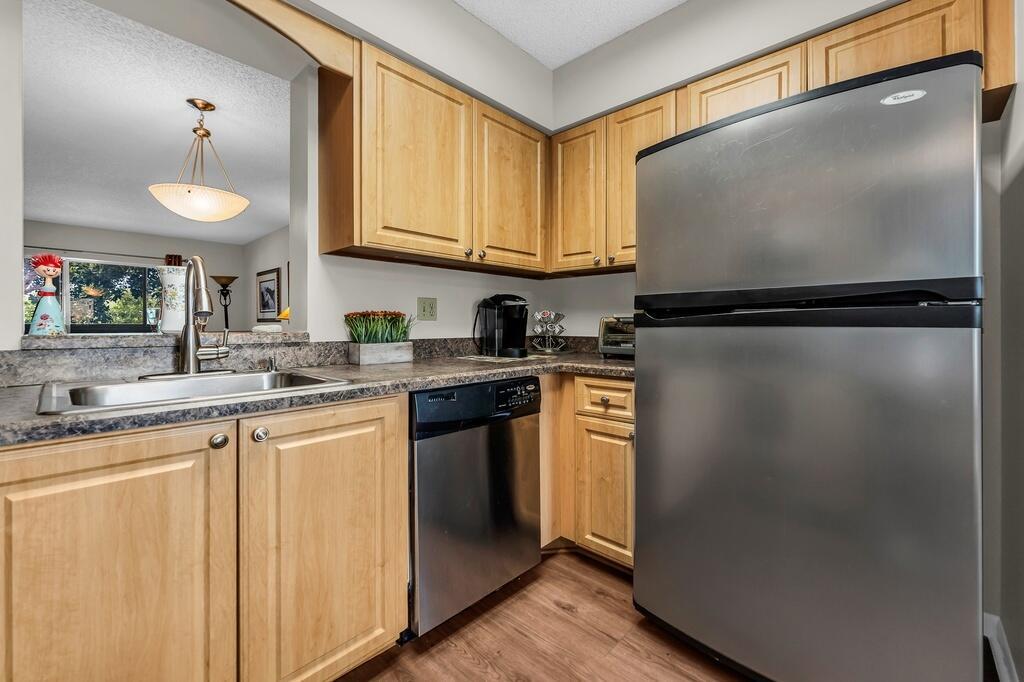 A kitchen with light wood cabinets, stainless steel appliances, and a pass-through window — 7341 Amberly Lane # 307, Delray Beach FL 33446, DELRAY BEACH, FL