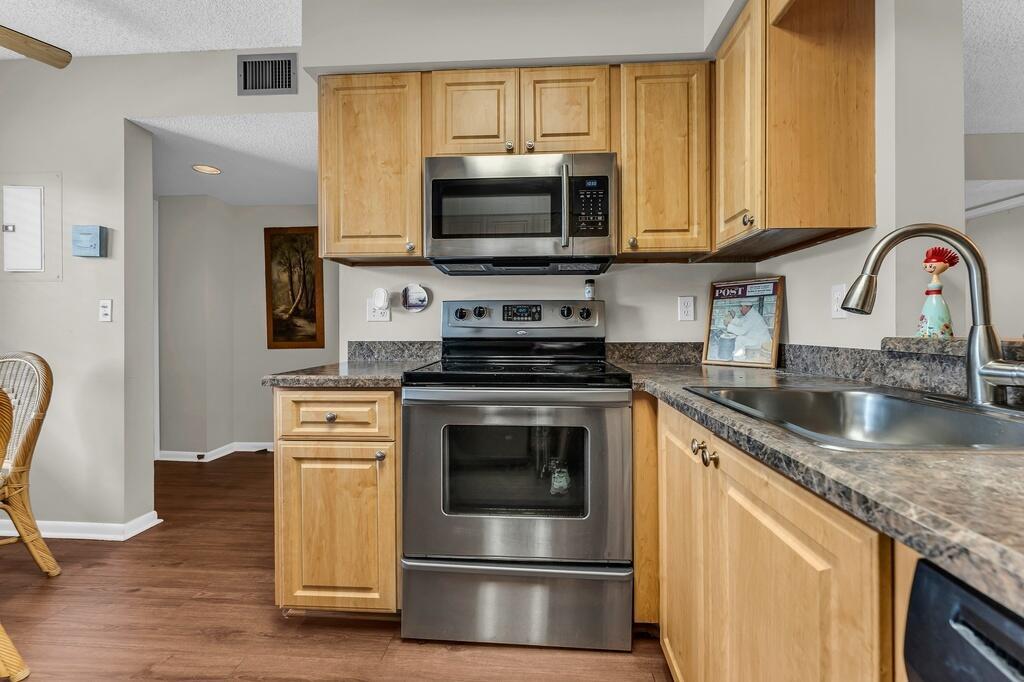 A kitchen features light wood cabinets, stainless steel appliances, and dark laminate countertops — 7341 Amberly Lane # 307, Delray Beach FL 33446, DELRAY BEACH, FL