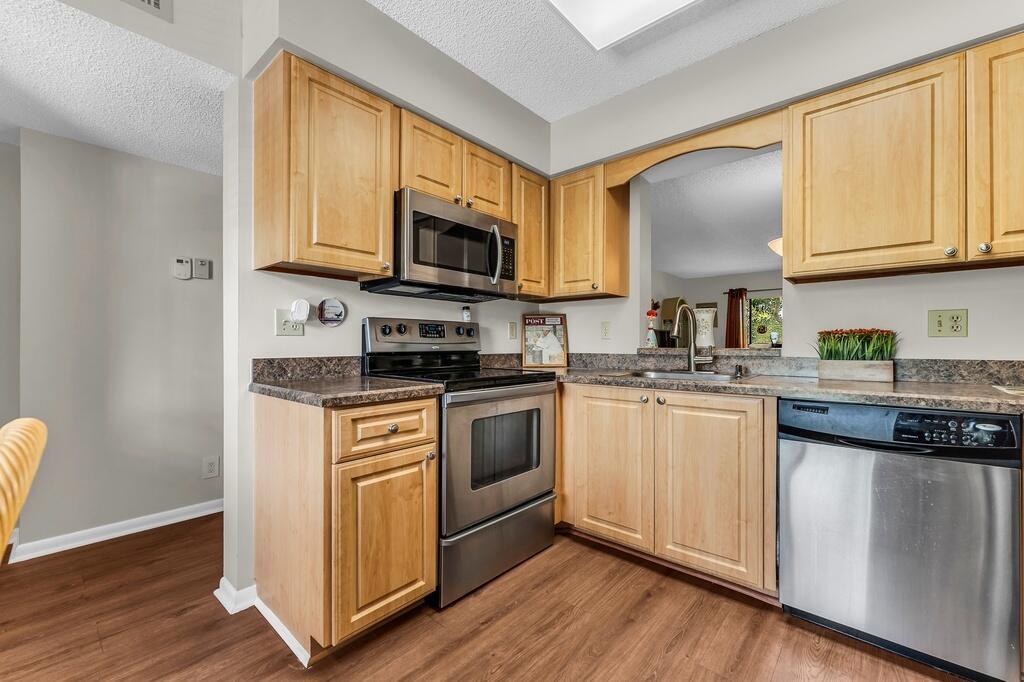 A kitchen with light wood cabinets, stainless steel appliances, and dark laminate countertops — 7341 Amberly Lane # 307, Delray Beach FL 33446, DELRAY BEACH, FL
