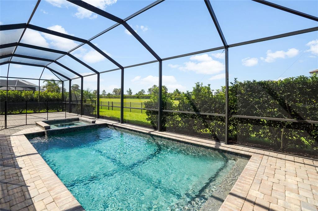 A screened-in swimming pool and spa with a paver deck overlooking a grassy backyard — 16228 TRADEWIND TERRACE, LAKEWOOD RANCH, FL