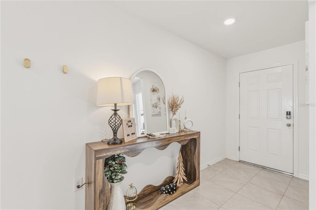 An entryway features a wood console table, a lamp, a mirror, and a white door — 2114 NW 246TH TERRACE, NEWBERRY, FL