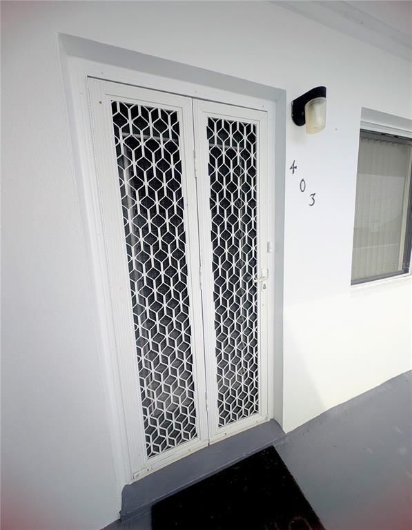 A white exterior door with a decorative metal security screen and the number 403 — 8055 112TH STREET UNIT 403, SEMINOLE, FL
