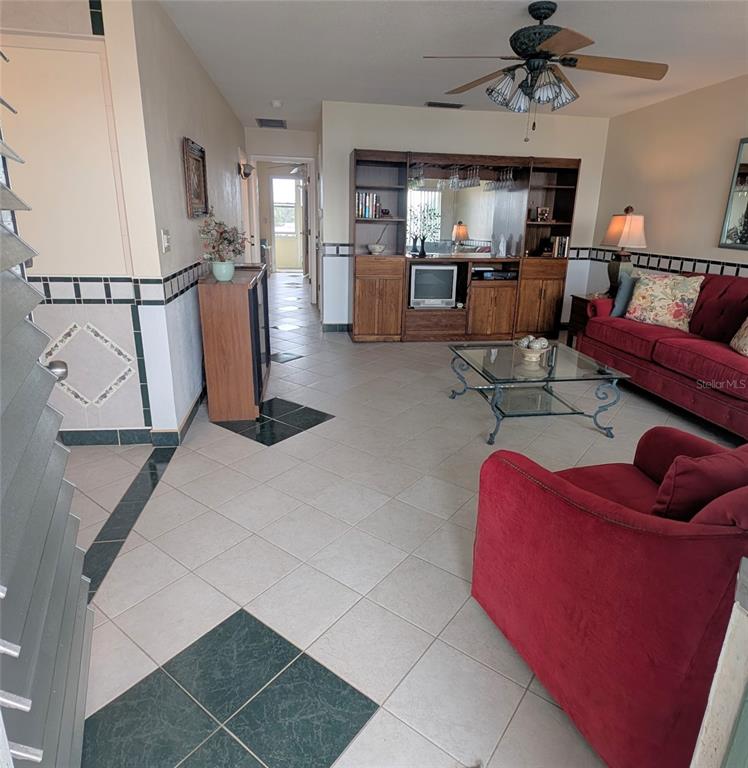 A living room features red furniture, a glass coffee table, and a built-in wooden wall unit — 8055 112TH STREET UNIT 403, SEMINOLE, FL