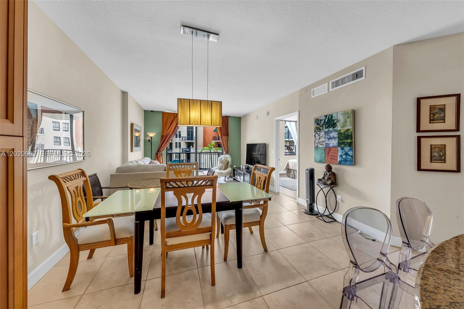 A dining area with a glass-topped table and wooden chairs sits before a living room — 55 Merrick Way # 709, Coral Gables FL 33134, CORAL GABLES, FL