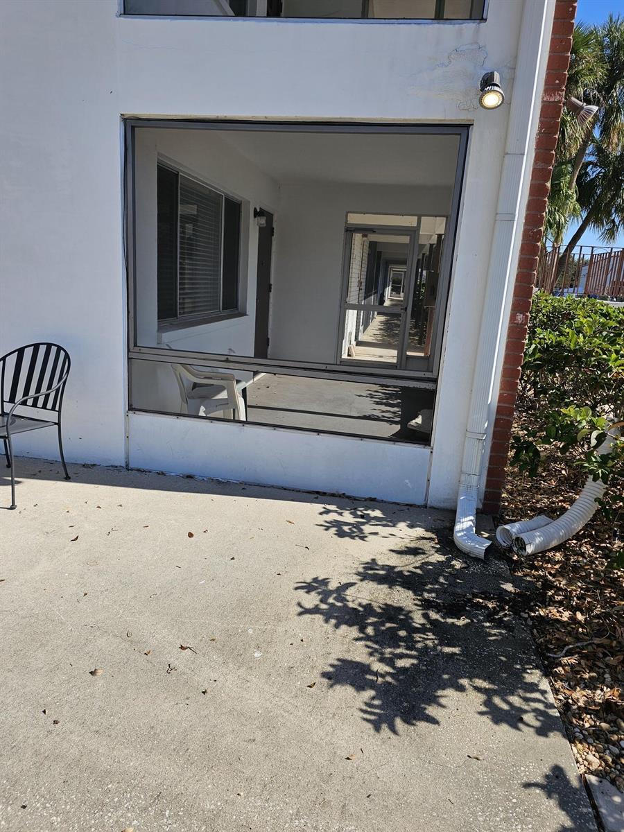 A ground-level concrete patio features a screened-in porch area with a metal chair — 2348 Shelley Street # 1, Clearwater FL 33765, CLEARWATER, FL