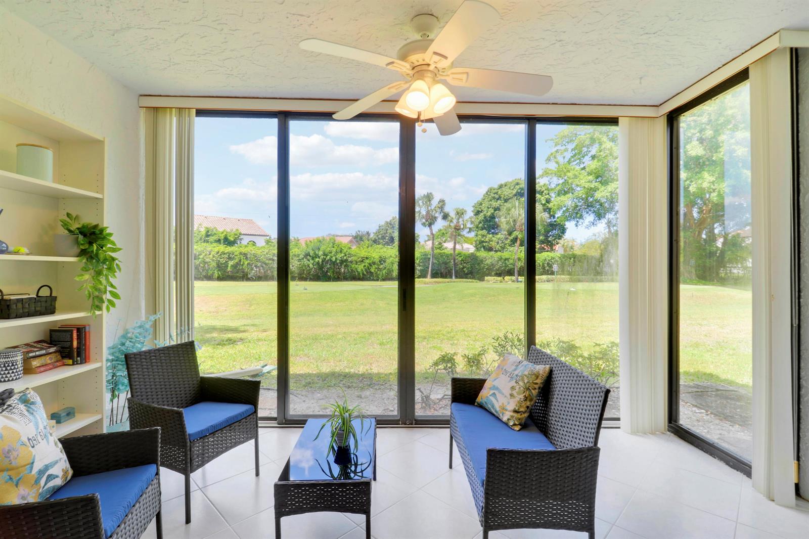 A sunroom with wicker furniture, a ceiling fan, and large windows overlooking a grassy lawn — 5121 Oak Hill Lane # 412, Delray Beach FL 33484, DELRAY BEACH, FL