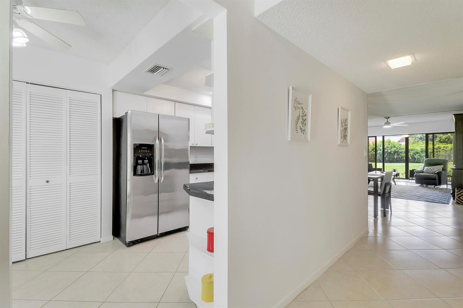 A kitchen with stainless steel appliances opens to a living area with tile flooring — 5121 Oak Hill Lane # 412, Delray Beach FL 33484, DELRAY BEACH, FL