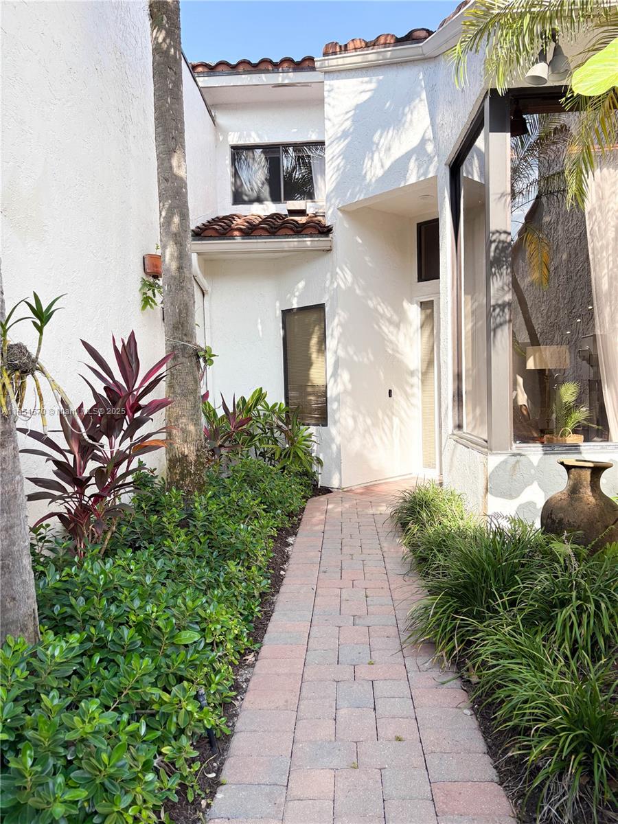 A brick walkway leads to the entrance of a white stucco house with tile accents — 2530 Windsor Way Ct, Wellington FL 33414, WELLINGTON, FL