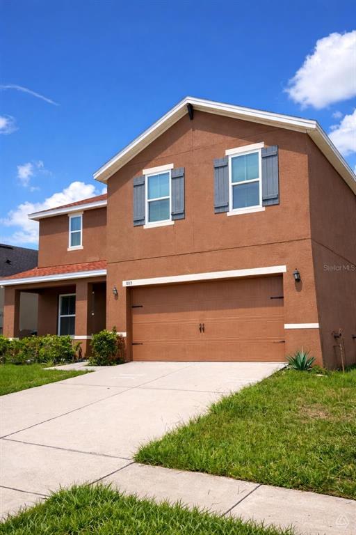 A two-story house with a brown stucco exterior and a two-car garage — 885 FREEDOM BOULEVARD, DAVENPORT, FL