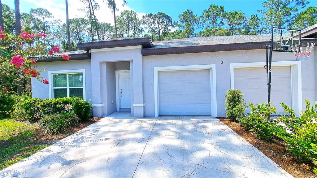 A single-story house with a two-car garage, a white front door, and a basketball hoop — 3 EASTERN PLACE UNIT A, PALM COAST, FL