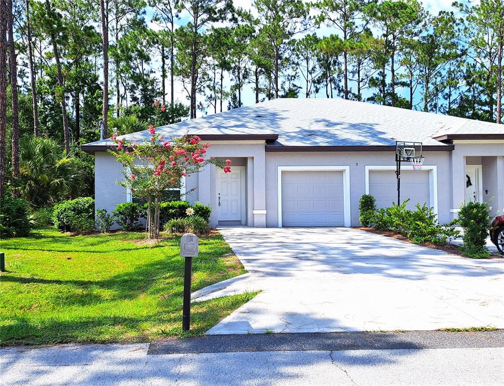 A single-story duplex with a concrete driveway, a garage, and a front yard with trees — 3 EASTERN PLACE UNIT A, PALM COAST, FL