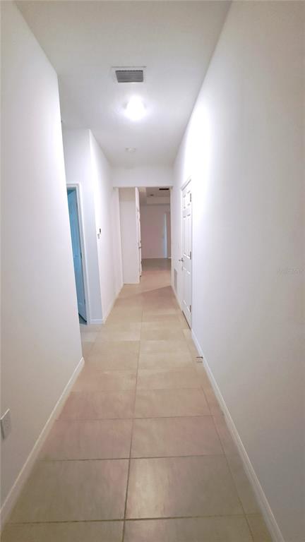 A long hallway with light-colored tile flooring and white walls leads to another room — 3 EASTERN PLACE UNIT A, PALM COAST, FL