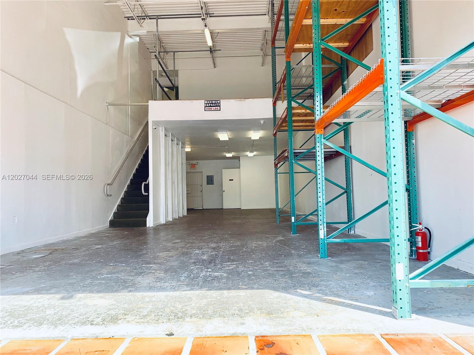 An industrial warehouse space features a mezzanine level, metal shelving units, and a staircase — 10421 NW 28 ST # 104, FL 33172, FL
