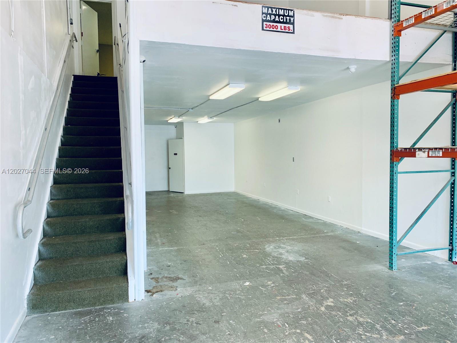 An industrial space features a carpeted staircase, a concrete floor, and metal storage shelving — 10421 NW 28 ST # 104, FL 33172, FL