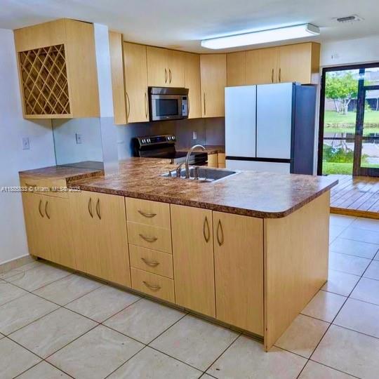 A kitchen features light wood cabinets, a granite countertop island, and a stainless steel refrigerator — 5164 S University Dr, Davie FL 33328, DAVIE, FL