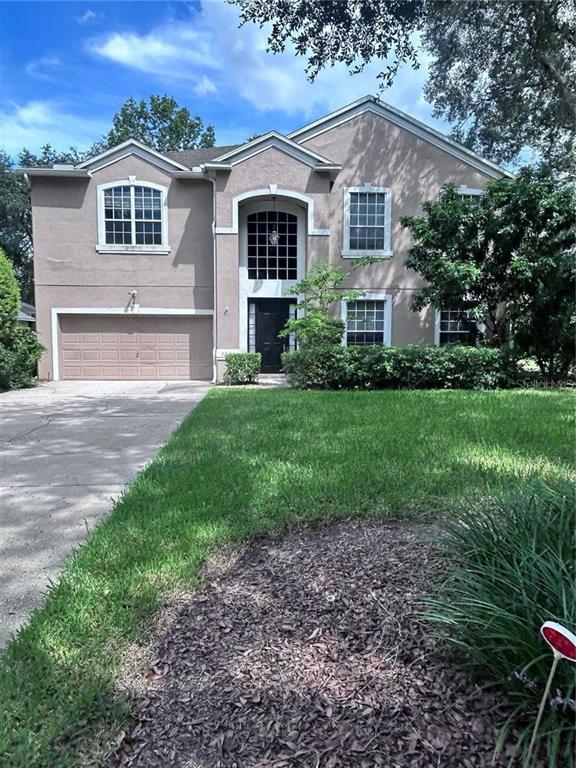 A two-story house with a tan stucco exterior, a two-car garage, and a front lawn — 1531 MCCREA DRIVE, LUTZ, FL