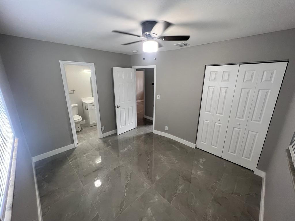 A bedroom with gray walls, large glossy floor tiles, a ceiling fan, and a closet — 151 NE 17th Avenue, Boynton Beach FL 33435, BOYNTON BEACH, FL