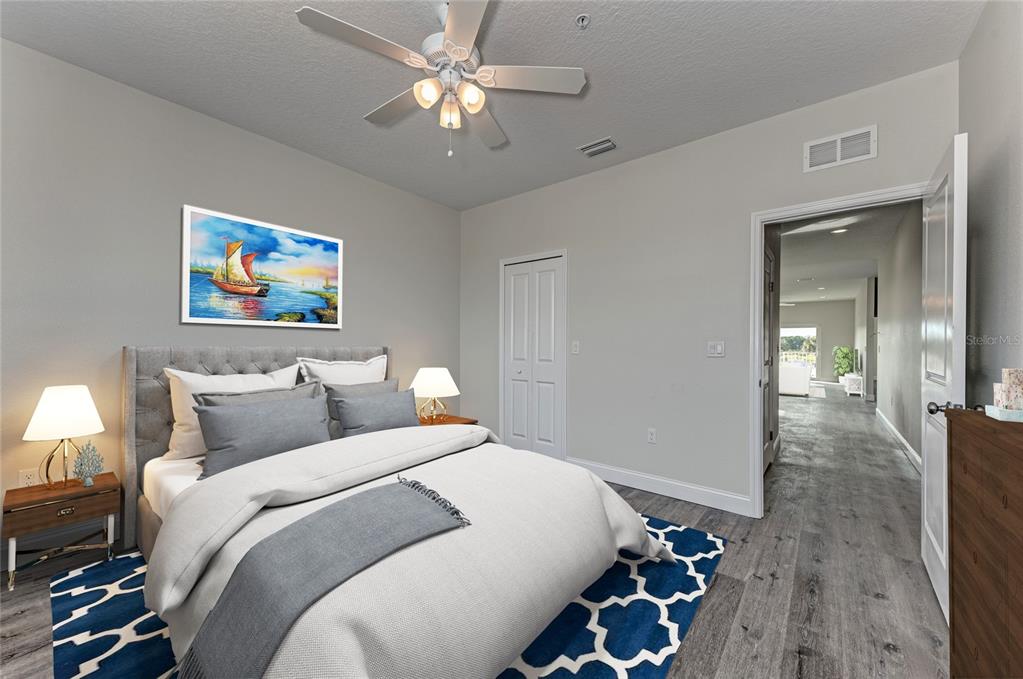 A bedroom features a gray upholstered bed, a blue patterned rug, and a ceiling fan — 2225 14TH AVENUE W UNIT 201, PALMETTO, FL