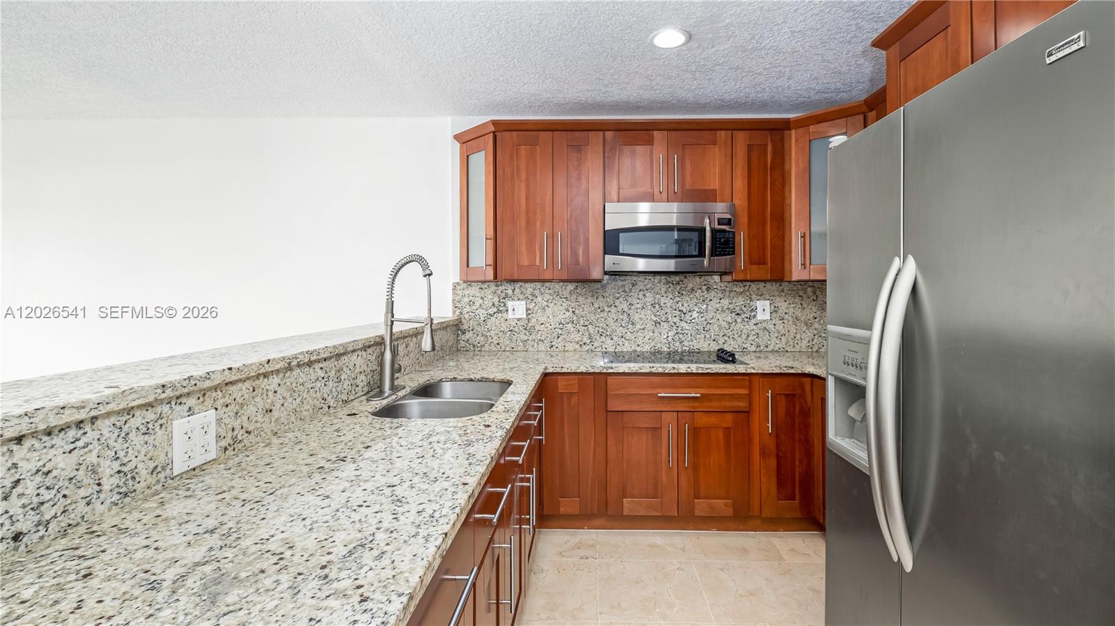 A kitchen features cherry wood cabinets, granite countertops, and stainless steel appliances — 4390 W 12th Ln # 18B, Hialeah FL 33012, HIALEAH, FL