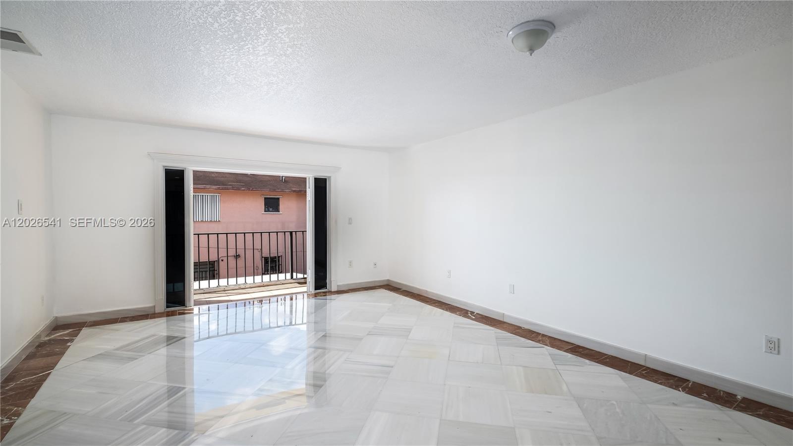 An empty room features white walls, marble flooring with a dark border, and a sliding glass door — 4390 W 12th Ln # 18B, Hialeah FL 33012, HIALEAH, FL