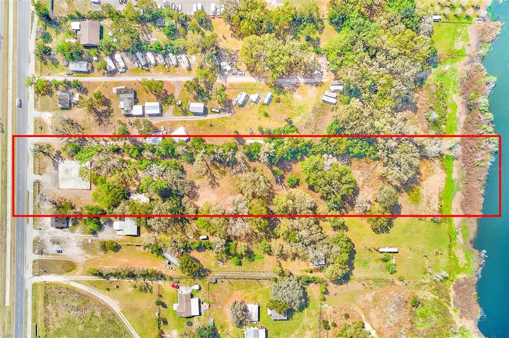 An aerial view shows a rectangular lot outlined in red extending from a road to water — 10351 US HIGHWAY 301, DADE CITY, FL