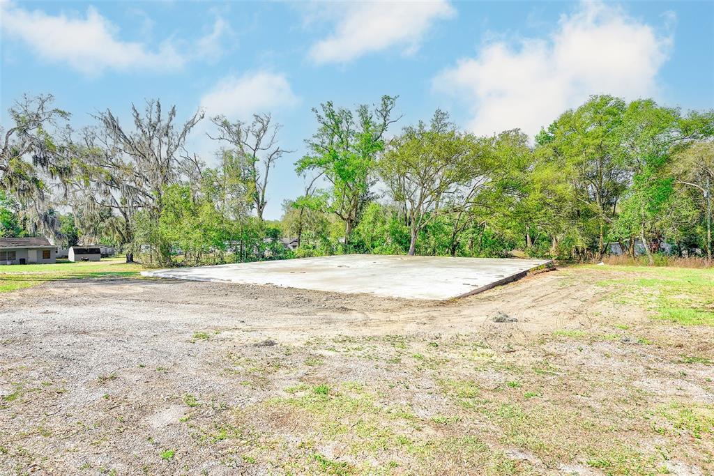 A large concrete slab sits on a grassy lot surrounded by trees — 10351 US HIGHWAY 301, DADE CITY, FL