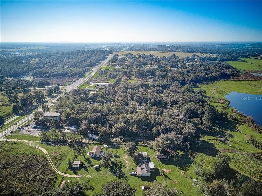 An aerial view shows a rural property with several houses, trees, and a nearby lake — 10351 US HIGHWAY 301, DADE CITY, FL
