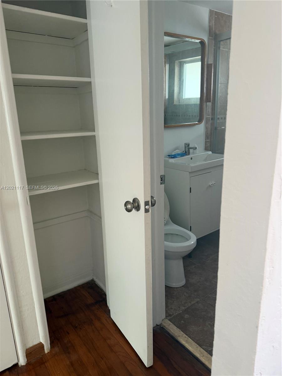 An open closet with white shelves sits next to a doorway leading into a bathroom — 500 77th St # 2, Miami Beach FL 33141, MIAMI BEACH, FL