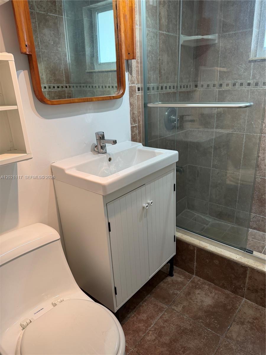 A bathroom features a white vanity, a wooden-framed mirror, and a tiled walk-in shower — 500 77th St # 2, Miami Beach FL 33141, MIAMI BEACH, FL