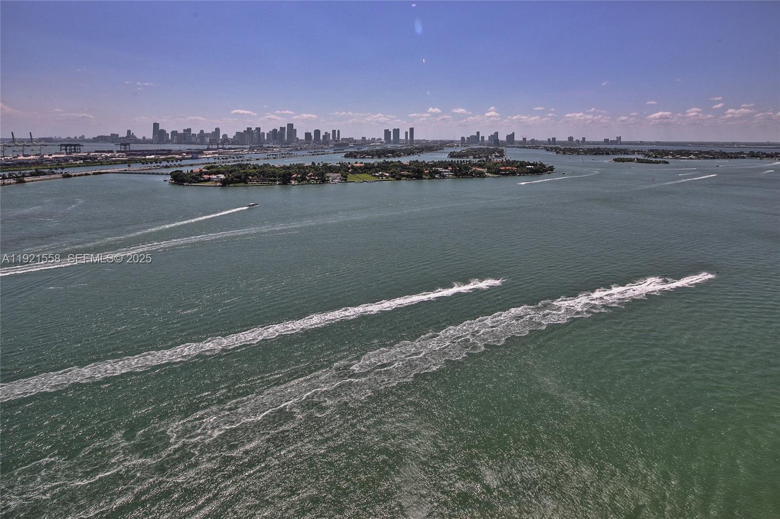 An aerial view shows a body of water with boat wakes and distant city skylines — 650 West Ave # 2801, Miami Beach FL 33139, MIAMI BEACH, FL