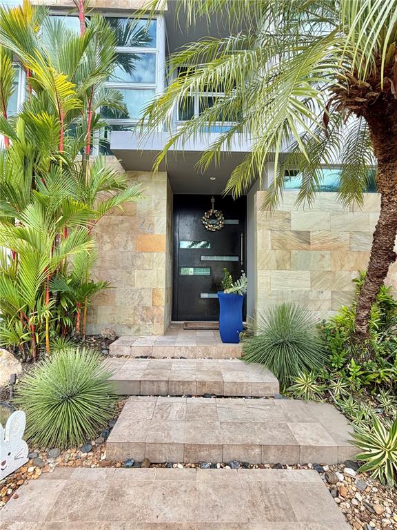 A modern home entrance features a dark door, stone facade, and tropical landscaping — 24 CALLE 3 SENDEROS DE MONTEHIEDRA, SAN JUAN, PR