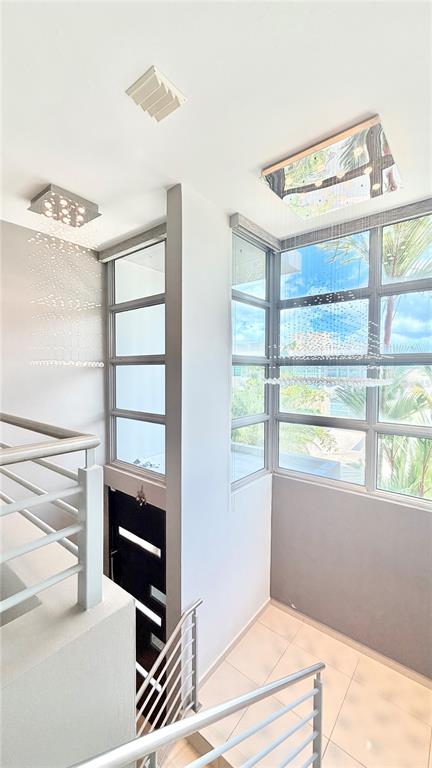 A modern staircase with metal railings leads toward a landing with large windows and chandeliers — 24 CALLE 3 SENDEROS DE MONTEHIEDRA, SAN JUAN, PR