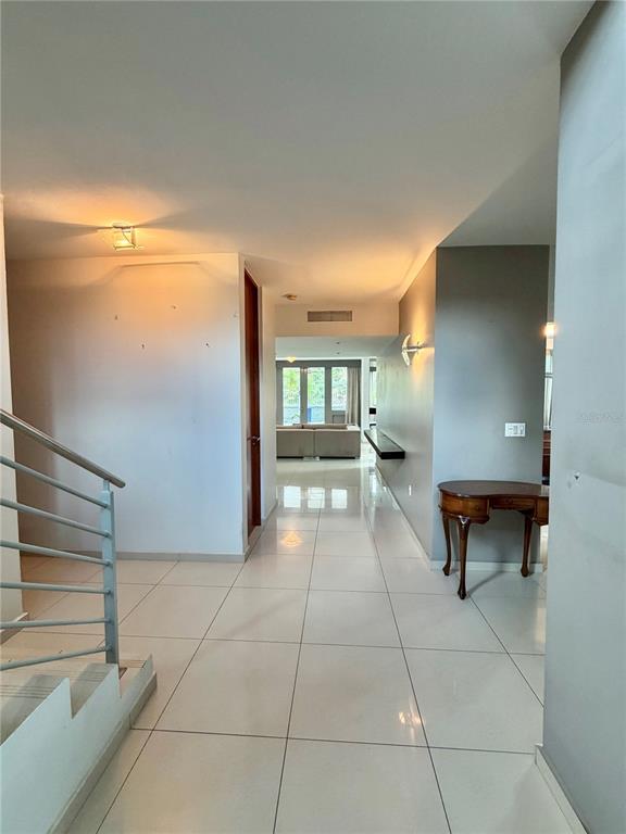 A hallway with white tile floors leads toward a living area with a sofa — 24 CALLE 3 SENDEROS DE MONTEHIEDRA, SAN JUAN, PR