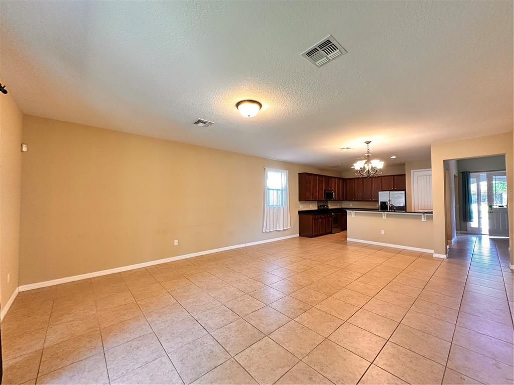 An open-concept living and dining area features beige walls, tile flooring, and a kitchen — 13330 LONGACRE DRIVE, WINDERMERE, FL