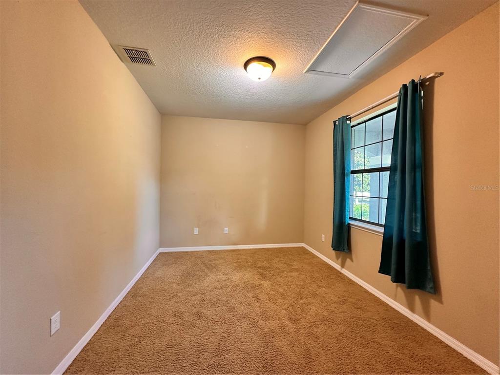 An empty room with tan walls, brown carpeting, a single window with curtains, and a light — 13330 LONGACRE DRIVE, WINDERMERE, FL