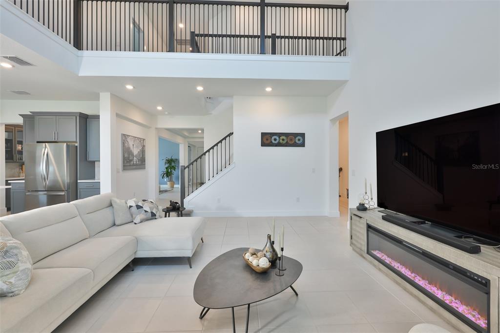 A modern living room features a white sectional sofa, a fireplace console, and a staircase — 6107 GOLDEN BEACH DRIVE, APOLLO BEACH, FL