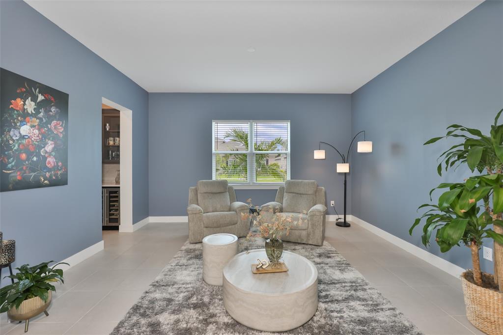 A living room with blue walls, two gray armchairs, a round coffee table, and rug — 6107 GOLDEN BEACH DRIVE, APOLLO BEACH, FL
