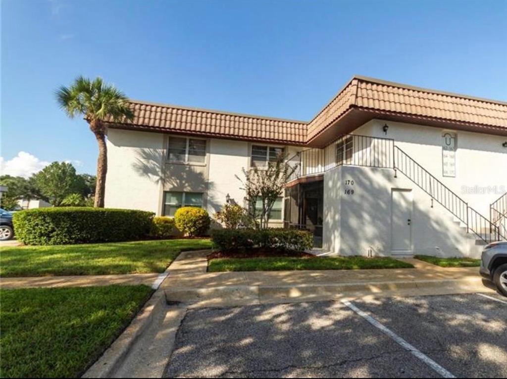 A two-story apartment building exterior with a brown tiled roof and a concrete staircase — 170 WINDTREE LANE, WINTER GARDEN, FL