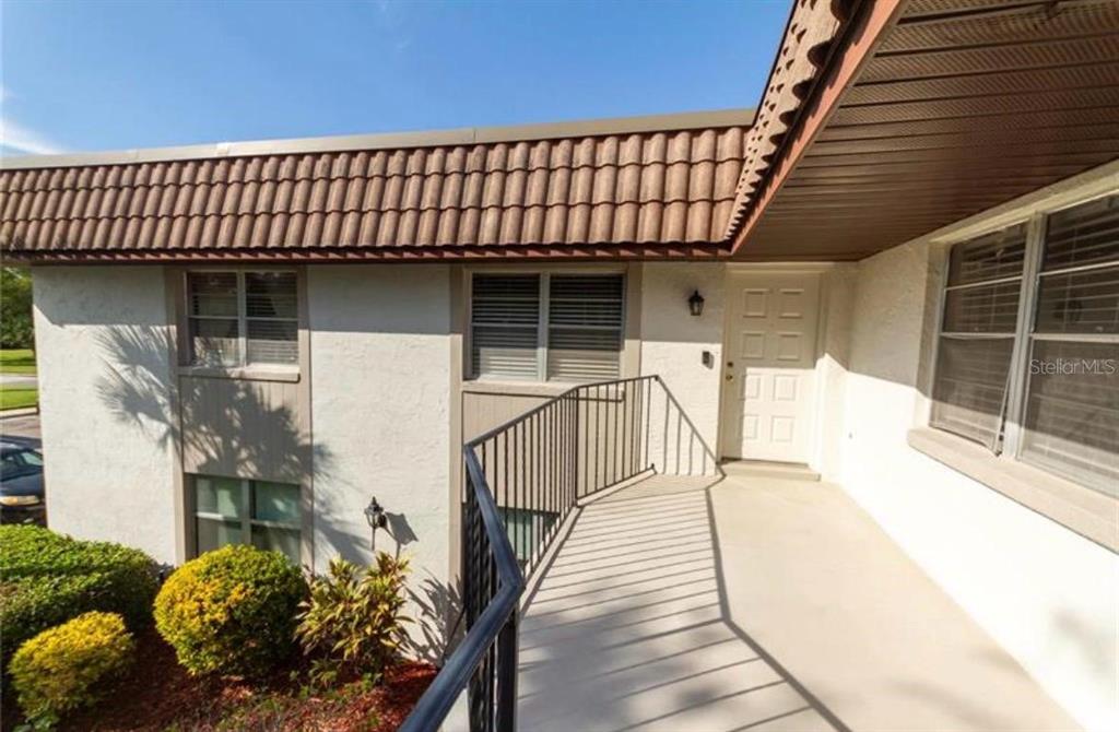 An exterior view shows a raised concrete walkway leading to a white front door — 170 WINDTREE LANE, WINTER GARDEN, FL