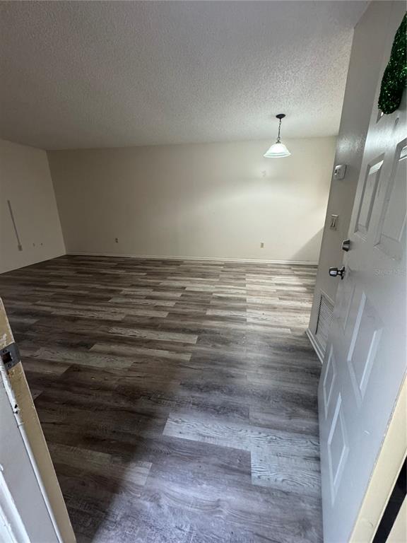 An empty room features wood-look laminate flooring, a white ceiling, and a hanging pendant light — 170 WINDTREE LANE, WINTER GARDEN, FL
